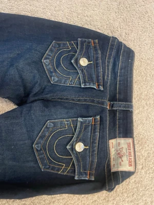 Mörkblå jeans från true religion - Säljer ett par true religion i storlek 24, skulle säga att de passar som S. De är använda ungefär 3-4 gånger, fint skick men kan vara lite upptrampade vid fötterna! 🩷