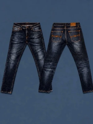 Nudie jeans - Snygga mötkblå nudie jeans med orange detaljer på bakfickorna. Perfekta för en trendig och avslappnad stil.  Längd 98 cm Bredd 38 cm