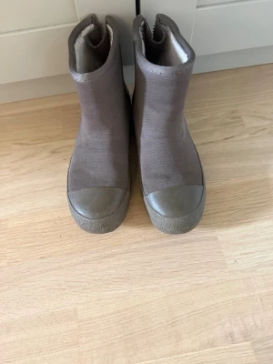 Beige stövlar från Tretorn - Säljer ett par bruna vinterskor från Tretorn med dragkedja på sidan och robust gummisula. Dragkjedan på ena skon är lite sönder men funkar fortfarande utmärkt att dra upp!