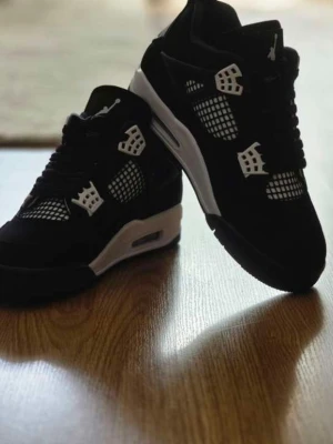 Svarta sneakers med vita detaljer - Säljer ett par svarta sneakers med vita detaljer och meshpaneler på sidorna. Skorna har en chunky sula och coola plastdetaljer vid snörningen. Perfekta för dig som gillar streetwear och vill ha en stilren look.