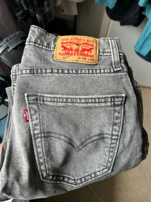Grå Levi's 502 jeans W29 L30 - Säljer ett par grå Levi's 502 jeans med klassisk femficksdesign och rakt ben. Jeansen har den ikoniska röda Levi's-lappen på bakfickan och patch i läder bak i midjan. Tillverkade i slitstark denim, perfekta för en avslappnad och trendig look.
