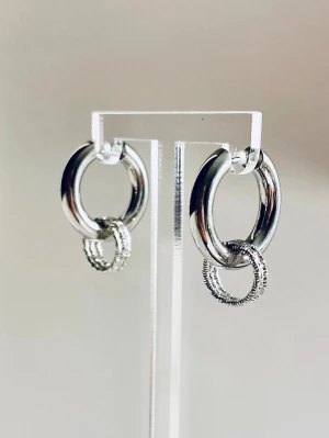 Silverfärgade dubbla hoops örhängen i rostfritt stål  - Snygga örhängen i silverfärg med tre  ringar i varje örhänge. Den större ringen är slät och blank medan den mindre har en detaljerad, texturerad yta. Perfekta för dig som gillar stilrena men ändå unika accessoarer.