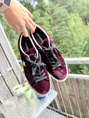 Unika Vinröda Converse sneakers i sammet - Unika, coola, edgy, burgundy Converse i mjuk sammet med vita sulor och svarta snören. Skorna har en vit converse-stjärndetalj på sidan, ca 3cm platå sula och låg modell. Perfekta för dig som vill sticka ut med en unik färg och material. Bekväma och använda endast en gång