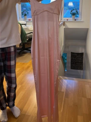 Ljusrosa långklänning i satin - Jag säljer denna rosa fina satin klänningen från Anderssons mode som är perfekt för tillfällen där man ska klä upp sig eller bara känna sig extra fin💕den är storlek S men är liten i storleken☺️ den är i perfekt skick, aldrig använd, bara prövad🤗 skriv vid minsta fundering!!