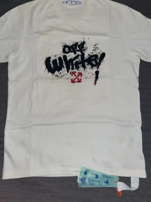 Vit Off-White t-shirt med Mona Lisa-tryck - Vit t-shirt från Off-White med stort grafiskt tryck framtill och bak, där baksidan har Mona Lisa-motiv och graffiti-inspirerad text. Klassisk passform och rund hals. Ikoniska Off-White-taggar hänger kvar. Perfekt för dig som gillar streetwear och konstnärliga prints. Priset kan diskuteras vad snabb affär.