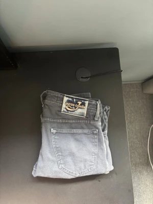 Blåa jeans från Jacob Cohen - Snygga blåa jeans från Jacob Cohen med klassisk femficksmodell och raka ben. Jeansen har en tydlig logotyp-patch bak i midjan och är tillverkade i mjukt denimtyg som ger en avslappnad men stilren look.