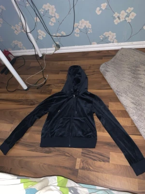 Mörk blå velour hoodie med dragkedja från juciy countour  - Snygg mörkblå hoodie i mjuk velour med dragkedja framtill och två fickor. Klassisk huva och ribbade muddar vid ärmslut och nederkant. Perfekt för en avslappnad och trendig look.