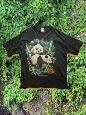 Vintage T-shirt | Panda - T-shirt med Panda tryck. L.P.S Amerikansk neck tag Äkta vintage så det är lite konstig passform, den sitter lite tight runt halsen för mig men tycker den är snygg ändå.  Normalt slitage för vintage i använt skick.  100% bomull  Skicka ett meddelande om du har frågor eller vill se fler bilder