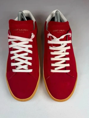Röda Saint Laurent sneakers i mocka - Snygga & trendiga Saint Laurent-skor 👞✨  Säljer ett par riktigt snygga och stilrena Saint Laurent-skor. Perfekta för dig som gillar en exklusiv och tidlös look.  👟 Storlek: 40 – upplevs dock som en stor 41:a 💰 Nypris: ca 8 000 kr 🛍️ Köpta på Plick: ca 2 500 kr 📦 Anledning till försäljning: De är tyvärr lite för stora för mig.  Skorna är riktigt snygga på och passar både till en mer dressad outfit och en avslappnad stil. Säljes eftersom storleken inte blev rätt för mig.  Obs: Jag rekommenderar att