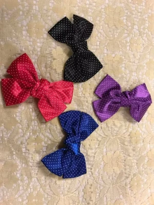 Färgglada prickiga hårrosetter - Fyra hårrosetter i satin med vita prickar i färgerna röd, svart, blå och lila. Rosetterna har metallclips på baksidan för enkel fastsättning i håret. Perfekt för att piffa upp frisyren med en söt detalj. 29kr/st 