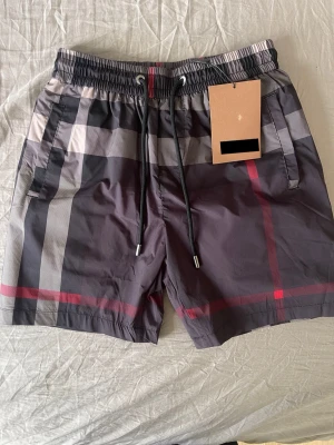 BB Bad-shorts  - Säljer ett par feta bb bad-shorts med svart och rött mönster