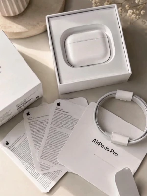 Apple AirPods Pro trådlösa hörlurar - Säljer ett par vita Apple AirPods Pro med laddningsetui och tillbehör. Hörlurarna är trådlösa och levereras i originalförpackning med laddkabel och manualer. Snygg och kompakt design i plast, perfekt för musik och samtal.