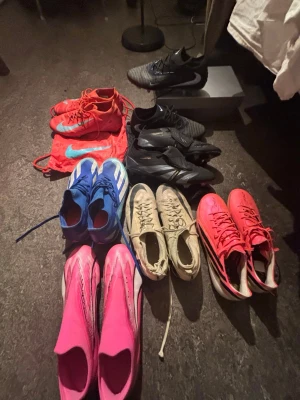 Flera par fotbollsskor i olika färger - Säljer ett gäng fotbollsskor i olika färger och modeller. Här finns skor i svart, blått, vitt, rosa och rött, flera med coola detaljer och loggor. Perfekt för dig som vill ha valmöjligheter på planen och gillar att sticka ut med färgglada skor.