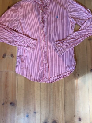 Rosa och vit randig skjorta Polo Ralph Lauren - Säljer en snygg rosa och vit randig skjorta från Polo Ralph Lauren i slim fit-modell. Den är storlek L men passar M också! Hör av er om funderingarna 🤩🙌🏼