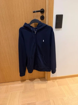 Mörkblå zip hoodie Ralph Lauren - Snygg mörkblå zip hoodie från Ralph Lauren. I nyskick då den i stort sätt oanvänd. Skick 9/10. 