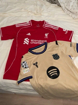 Liverpool och Barcelona matchtröjor - Säljer två fotbolls tröjor från 25/26 säsongen, Liverpool Hemma tröja storlek ”M” salah 11 på ryggen, Barcelona borta tröja Lamine yamal på ryggen  storlek ”S”  399 för en tröja och 650 för båda