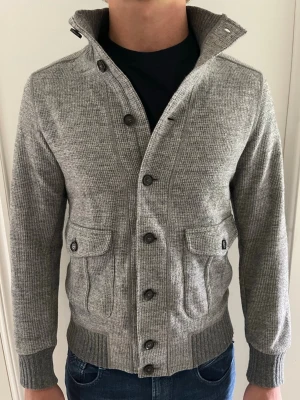 Eleventy Milano cardigan - Grå stickad cardigan Eleventy Milano, nypris cirka 9000. Grym kvalitet, modell på bild 182cm 78kg sitter något litet, passar ca 170-180. Liten defekt syns på sista bilden. Tveka inte på att skriva vid minsta fundering