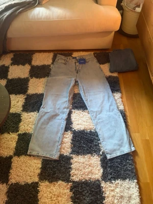 Ljusblå raka jeans, halvbaggy  - Säljer ett par ljusblå raka jeans med klassisk femficksdesign och normal passform. Jeansen har hög midja och är tillverkade i bomull för en skön och avslappnad look. Perfekta till vardags och lätta att matcha med olika stilar. , helt oanvända nypris 799 säljer för 