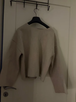Beige oversized tröja med vida ärmar - En stilren beige tröja med oversized passform och vida, långa ärmar. Tröjan har en rak, något kortare modell och är tillverkad i ett mjukt material som känns skönt mot huden. Perfekt för en avslappnad och trendig look.
