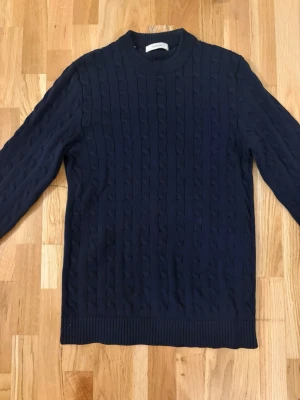 Stickad Tröja - Snygg mörkblå kabelstickad tröja med rund hals och långa ärmar. Har en klassisk och stilren look. Perfekt för dig som gillar enkel men trendig stil. Perfekt skick utan några defekter. Storlek M, Pris kan diskuteras. 