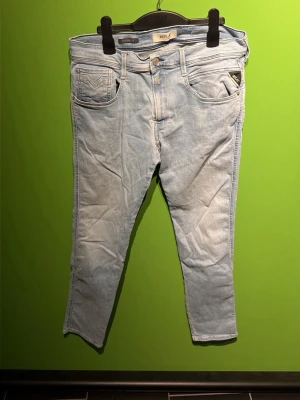 Ljusblå slim fit jeans Replay - Snygga ljusblå jeans i slim fit-modell med klassisk femficksdesign och normal midja. Jeansen har en fräsch tvätt och raka ben, perfekta till sneakers eller boots. Materialet är mjukt denim som ger en skön känsla hela dagen.