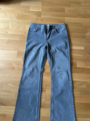 Blå bootcut jeans med hög midja - Säljer ett par klassiska blå bootcut jeans med hög midja och fem fickor. Jeansen har en snygg tvätt och vida ben som ger en retrovibe. Perfekta att styla med sneakers eller chunky boots. Materialet är denim i bomull.