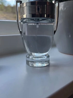 Invictus Paco rabbane - Ny pris cirka 800 mitt pris 400 och knappt andvänd som ni ser på bilderna😃.                   Säljer en unik parfymflaska i genomskinligt glas med silverfärgat lock och detaljer. Flaskan har formen av en pokal med två handtag på sidorna och en bred botten. Perfekt för dig som gillar snygg design på parfymflaskor.