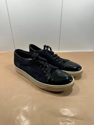 Lanvin skor - Sjukt snygga lanvin skor till salu är, perfekta för sommaren! Skorna är storlek 9 vilket tyder på storlek 43! Grymt skick, ser exakt ut som bilderna så avgör själv bara en liten detalj det finns smycket små röda prickar på ena framsidan som jag tror kan försvinna med lite arbete testade inte själv men annars syns det knappt ! Färgen är navy blue och inget medföljer! Skriv gärna vid fler frågor🙏