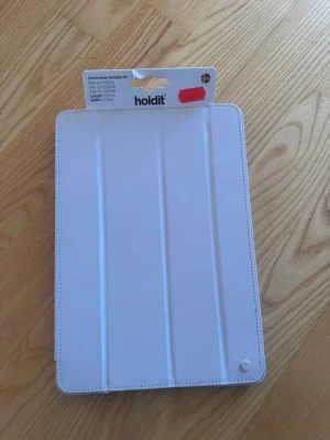Vit iPad smart cover från Holdit - Snyggt vitt smart cover till iPad 10.2 tum (2019, 2020, 2021) från Holdit. Fodralet är gjort i ett slätt material och har vikbar framsida som skyddar skärmen. Perfekt för att hålla din iPad säker och stilren. Helt oanvänt 