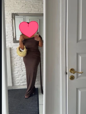 Brun offshoulder långklänning - Snygg brun långklänning med offshoulder-design och figurnära passform. Klänningen har en elegant och enkel stil som framhäver siluetten. Perfekt för dig som gillar stilrena och trendiga looks.
