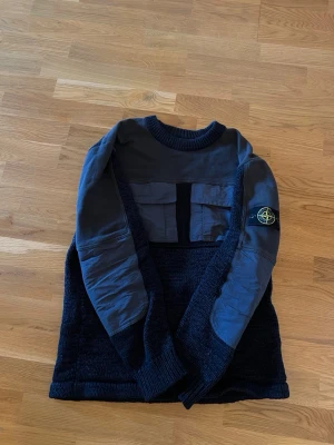 Stone Island SS19 Nylon Webbing Knit 7015568D8 - Riktigt snygg och mer ovanlig Stone Island-modell med stickad konstruktion, nylonpaneler, dubbla bröstfickor och den klassiska Compass-badgen på armen.  100% äkta och verifierad via Certilogo. Köpt ny på NK, men inget kvitto kvar.   Begagnat men fint skick. Se bilder för skick och detaljer. (Finns en riva vid nacken där bak)   Säljes då den inte längre kommer till användning.
