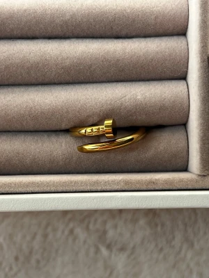 Guldfärgad ring i spikdesign - Cool ring i guldfärgad metall med unik spikdesign som ger en edgy och modern känsla. Ringen är öppen och justerbar, vilket gör den enkel att anpassa efter fingerstorlek. Perfekt accessoar för dig som gillar statement-smycken och vill sticka ut.Aldrig använd. 