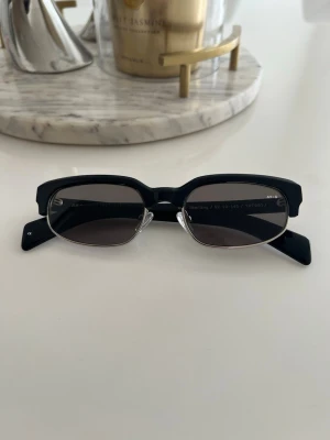 Svarta rektangulära solglasögon - Snygga solglasögon med svart, tjock båge och rektangulära linser. Glasen är mörka och ger en cool, modern vibe. Perfekta för dig som vill sticka ut med en stilren accessoar till sommaren.The sun lenses are Columbia Resin 39 (CR39) with an anti-reflection coating on the inside and a special UV filter with protection up to 400 nm and an index of 1.5. Lens category 3: The sunglasses provide a high level of sun glare reduction and good UV protection. 