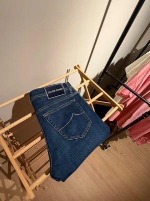 Blå jeans från Jacob Cohen - Snygga blå jeans från Jacob Cohen med klassisk femficksdesign och kontrastsömmar. Jeansen har en mörkblå tvätt och en patch med logga bak i midjan. Perfekta till en avslappnad och stilren look. Nypris 5900kr köpta för några veckor sedan! 