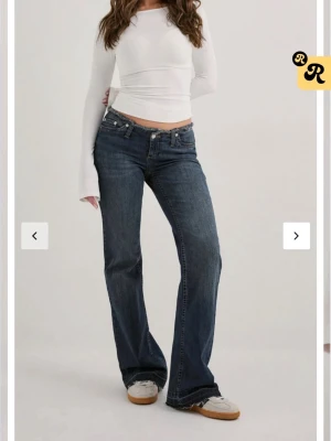 Mörkblå bootcut jeans med råa kanter - Snygga mörkblå bootcut jeans med råa, fransiga benslut och klassiska fem fickor. Jeansen har låg midja och en lätt tvättad look. Perfekta för en avslappnad och trendig stil.