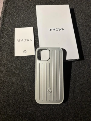 Rimowa mobilskal IPhone 15 - Snyggt och stilrent mobilskal från Rimowa i silverfärgad metall-look. Skalet har vertikala ränder och en öppning för kameran. Passar perfekt för dig som vill ha ett exklusivt och tåligt skydd till din mobil. Levereras i originalförpackning.