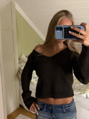Brun stickad tröja - Mysig brun stickad tröja med croppad passform och v-ringad hals. Tröjan har långa ärmar och en avslappnad, lite lös siluett som kan bäras off-shoulder. Perfekt att matcha med jeans eller kjol för en chill look.
