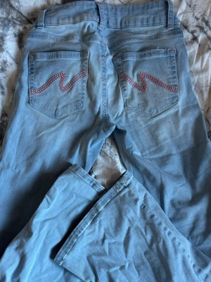 Nelly jeans - Fina jeans med rosa detaljer, från Nelly. Har en fläck vid innerbenet på en sida vilket säkert skulle kunna gå bort. Även repats upp av att dom varit lite för långa. Annars snygga