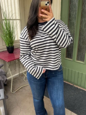 Randig långärmad topp - Snygg långärmad topp med mörkblå och vita ränder. Modellen är loose fit med breda ärmar och rund halsringning. Tillverkad i mjuk bomull, perfekt för en avslappnad och trendig look.