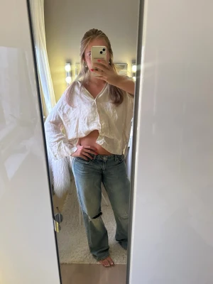 Baggy ljusblå slitna jeans - Säljer ett par baggy ljusblå jeans med raka ben och slitningar på båda knäna. Jeansen har en avslappnad passform och klassisk femficksdesign. Perfekta för en chill och trendig look.