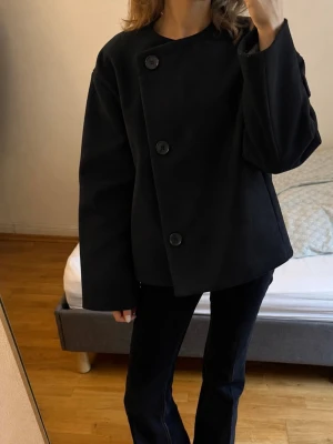 Svart kappa med stora knappar - Wool-blend jacka från BikBok i storlek XS.               Nypris - 999 kr
