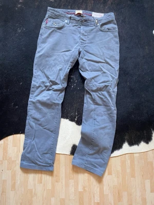 Blå raka tramarossa jeans - Snygga blå tramarossajeans med rak passform och klassiska fem fickor. Byxorna har bälteshällor och stängs med knapp. Perfekta för dig som gillar en avslappnad men ändå stilren look.