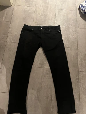 Svarta jeans från Replay, stl 40 - Snygga svarta jeans från Replay i klassisk femficksmodell. Jeansen har raka ben och normal midja, perfekta för en stilren look. Tillverkade i ett mjukt och stretchigt material som ger skön passform hela dagen.