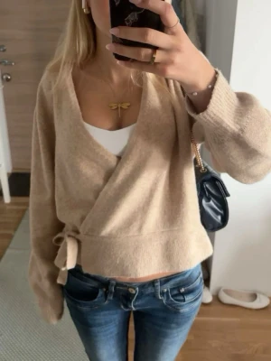 Beige omlottkofta med knyt - Säljer denna supersnygga omlottkoftan från & other stories! Supersnygg och mysig till hösten och vintern! Bra skick och använd några gånger men varsamt. 🥰
