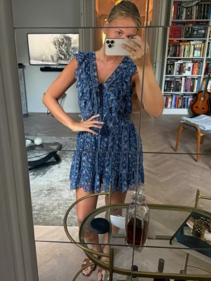 Blå blommig volangklänning - Söt blå kortklänning med volang💙💙Endast använd vid några få tillfällen, så i nyskick. Köpt från märket Pepe Jeans London, köpt för cirka 1000 kr. Så fina detaljer!! Skriv för fler bilder💕💞💓
