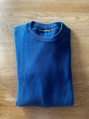 Mörkblå stickad tröja J.Lindeberg - Snygg mörkblå stickad tröja från J.Lindeberg. Tröjan har rund halsringning och långa ärmar. Perfekt för dig som gillar stilrena plagg 