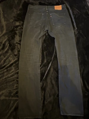 Levi’s 501 jeans - Säljer ett par svarta Levi’s 501 jeans med klassisk rak passform och fem fickor. Jeansen har bälteshällor, knappgylf och subtila sömmar. Materialet är denim och de har en enkel, stilren look som passar till det mesta. Storlek: W32 L36
