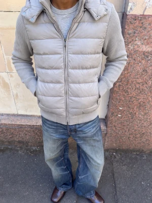 Ljusgrå dunväst med huva - Snygg ljusgrå dunväst från Eden Marco med avtagbar huva och stickade ärmar. Västen har quiltad design, dragkedja framtill och ribbade muddar. Perfekt för lager-på-lager och streetwear-vibe.