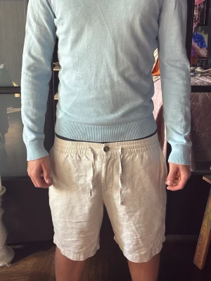 Ljusblå rundhalsad stickad tröja - Ljusblå stickad tröja med rund hals och långa ärmar. Tröjan har ribbade muddar vid ärmslut och nederkant för en tajt och clean passform. Perfekt för dig som gillar en enkel men fräsch stil.