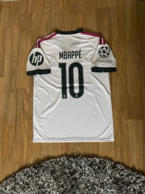 Real Madrid Mbappé #10 Hemmatröja 2026/27 – Storlek M - Helt ny Real Madrid hemmatröja 2026/27 i storlek M med lappar kvar. Mbappé #10 på ryggen samt Champions League-, UEFA Foundation- och HP-märken. 100 % polyester och skön passform. Passar ca 170–180 cm / 60–80 kg. Hör gärna av dig för fler bilder eller frågor!